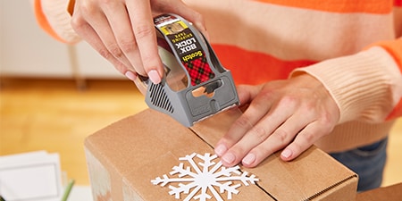 Zamykanie świątecznego prezentu w paczce przy użyciu Taśmy Scotch® Box Lock™
